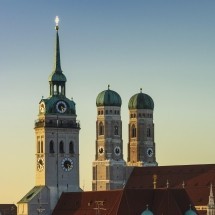 Die Kirchtürme der Münchner Frauenkirche vor einem abendlichen Himmel.